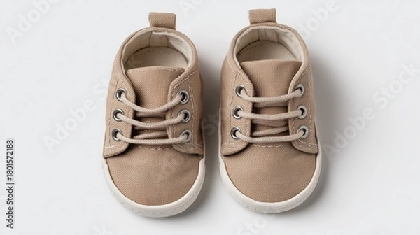 Fototapeta Studio image of baby shoes placed neatly on a white background, soft shadow lighting.