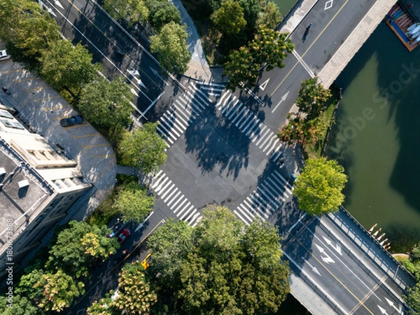 Fototapeta Aerial view of a crosswalk intersection with trees and a river