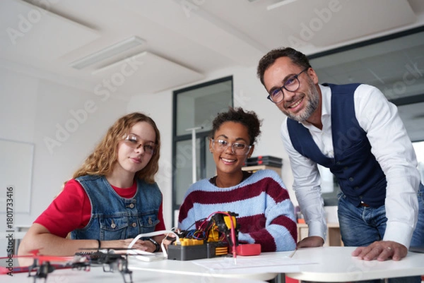 Fototapeta High school students working on robotics project with their teacher.