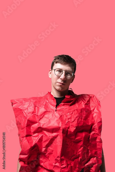 Fototapeta A young person stands confidently against a bright pink background, wearing a unique, crumpled red outfit that adds a playful, artistic flair to the scene