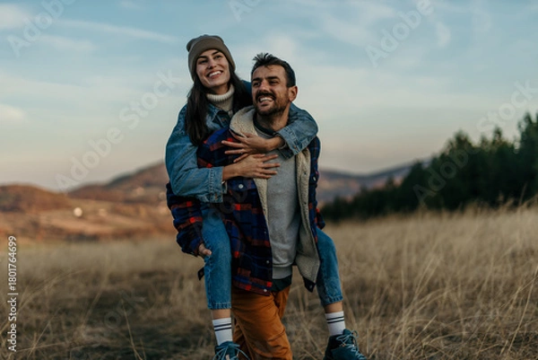 Obraz Couple piggybacking outdoors experiencing fun and togetherness