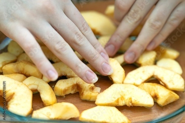 Obraz Arranging sliced apple segments in a glass bowl for making a traditional Charlotte pie