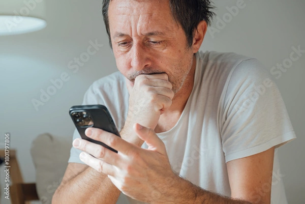Obraz Bored adult male distracted and idle on phone, doom scrolling and procrastinating with blank expression and low energy mood.