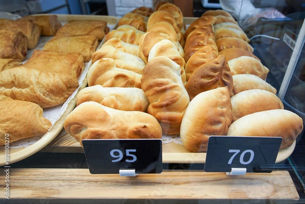 Obraz Freshly baked buns and pies made from wheat bread are on display for sale on a shelf in the store.