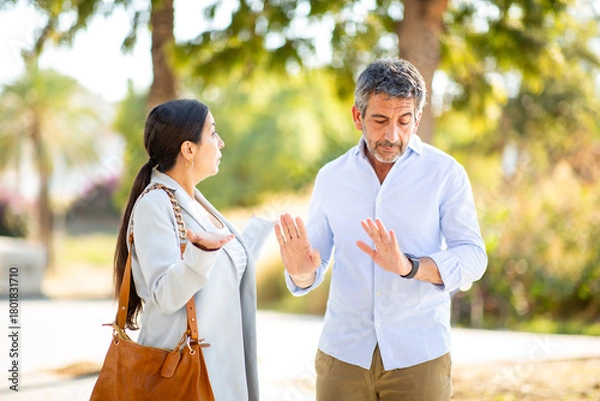Obraz Couple arguing with defensive gestures in a heated outdoor discussion