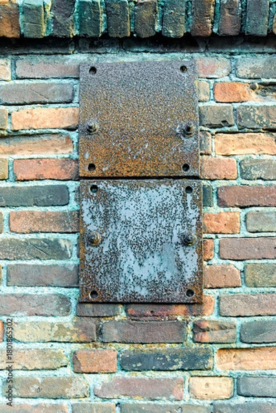 Obraz two square rusty metal plates attached to a stone wall