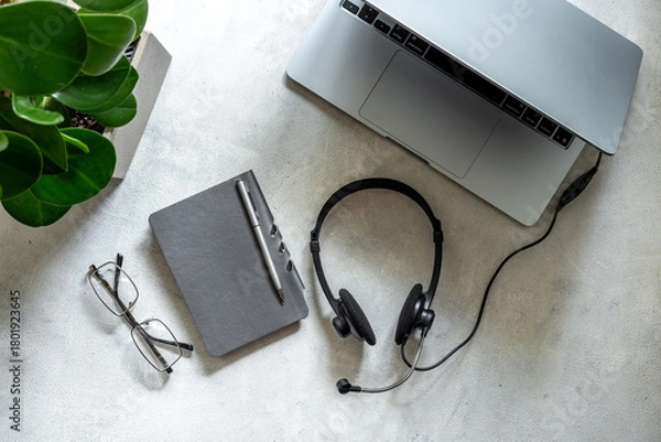 Fototapeta Headset and laptop - customer support equipment at call center, top view. Online conference work space. Online education concept