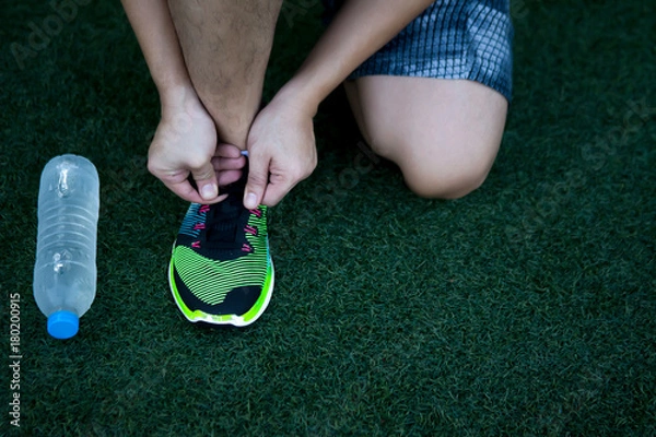 Fototapeta Sport man who has more experience by look at scar at leg and scratch at his shoe prepare himself before his activity.
