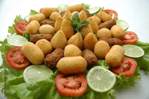 Obraz Flat lay of a Brazilian appetizer platter with fried snacks, lettuce, tomato, and lime. Perfect for food blogs, menus, or party planning content.