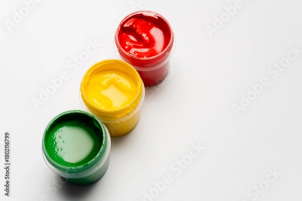 Obraz Jars of multi-colored gouache on a white background. Green, red, and yellow traffic light colors.