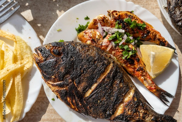 Obraz El Jem, Tunisia A plateof barbequied fresh fish with lemon and french fries.