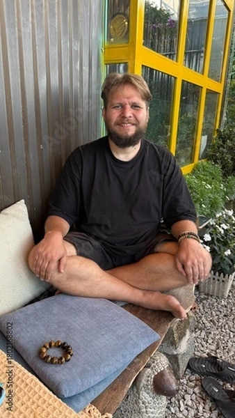 Obraz Portrait of a Smiling, Bearded Man Relaxing Cross-legged on a Bench Outdoors