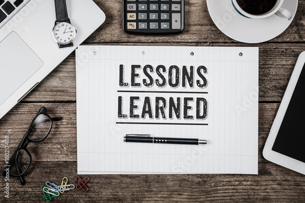 Obraz Lessons learned statement on notepad on office desk from above