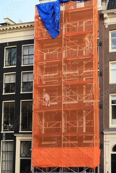 Fototapeta Scaffolding with Orange Construction Screen in Amsterdam, Netherlands