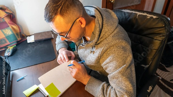 Fototapeta Young man writing in a notebook