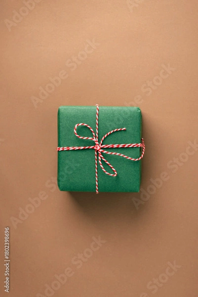 Obraz Christmas gift with a bow on a beige background, top view, minimalist, zero-waste concept