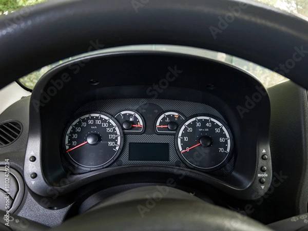 Fototapeta Closeup of a modern car dashboard showing speedometer tachometer fuel and temperature gauges with clear analog design and black background.
