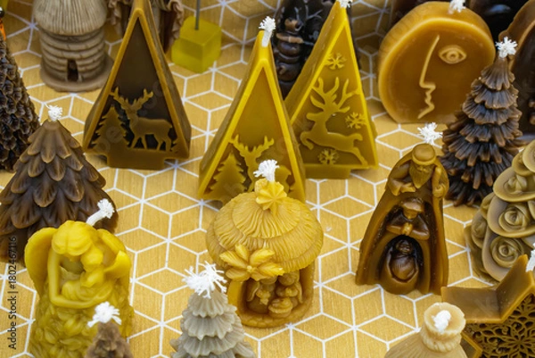 Fototapeta Candles in various shapes arranged on a patterned surface showcasing winter and festive decorations in a cozy market setting