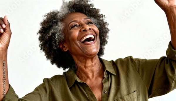 Obraz Joyful senior African American woman celebrating with a happy laugh. Portrait of a successful and vibrant elderly Black female with arms raised on a white background
