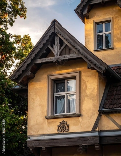 Fototapeta Close-up of a rustic building with ornate trim and windows, golden light