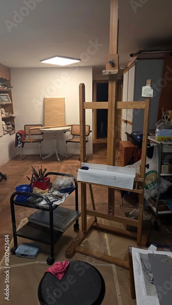 Fototapeta Creative workspace with easel and art supplies in cozy artist's studio setting