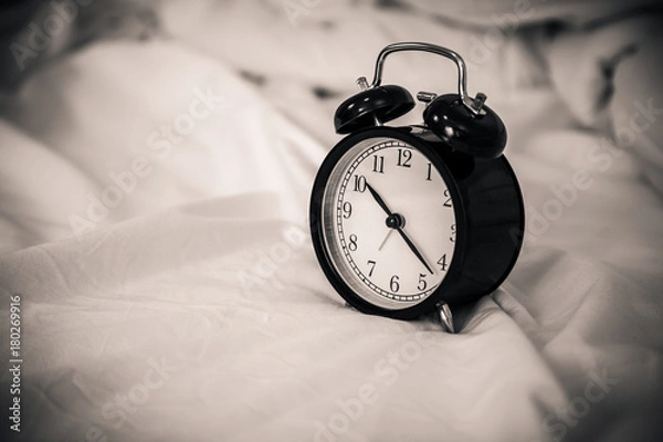 Fototapeta black alarmclock on white bed with free copyspace for your creativity ideas text