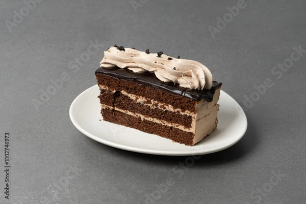 Fototapeta Chocolate cake slice with creamy frosting on a plate ready to be enjoyed
