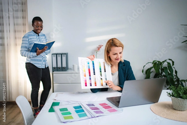 Fototapeta Coworkers discussing color palette during video call in office