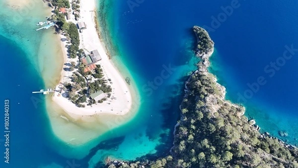 Fototapeta A drone view of the Ölüdeniz peninsula and its turquoise lagoon on the Mediterranean coast of Turkey, surrounded by forested mountains and clear blue water.