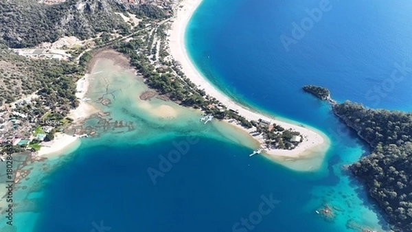 Fototapeta A drone view of the Ölüdeniz peninsula and its turquoise lagoon on the Mediterranean coast of Turkey, surrounded by forested mountains and clear blue water.