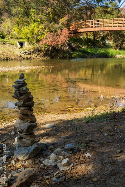 Obraz Stacked River Stones with Autumn Forest Bridge