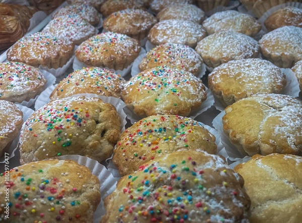Fototapeta A close-up view of traditional Italian cookies, likely Anginetti (Italian Wedding Cookies) or similar soft Italian cookies, dusted with powdered sugar and decorated with rainbow sprinkles. 