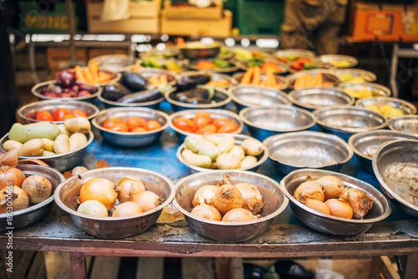 Fototapeta Bowls of onions, tomatoes, potatoes, and eggplants displayed at an outdoor market stall