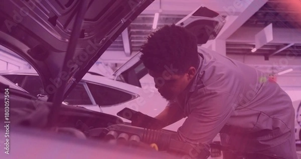 Obraz Leaning mechanic in gray work shirt inspecting engine bay under raised hood at shop, holding phone