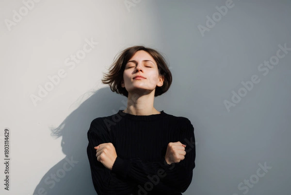 Obraz young woman standing with her fists pressed against her chest radiating energy and determination