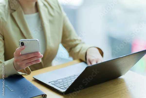 Obraz パソコンとスマートフォンを使うビジネスパーソン