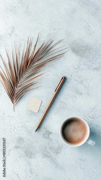 Fototapeta A flat lay composition featuring a dry palm leaf, a pen, a sticky note, and a cup of coffee on a textured surface.