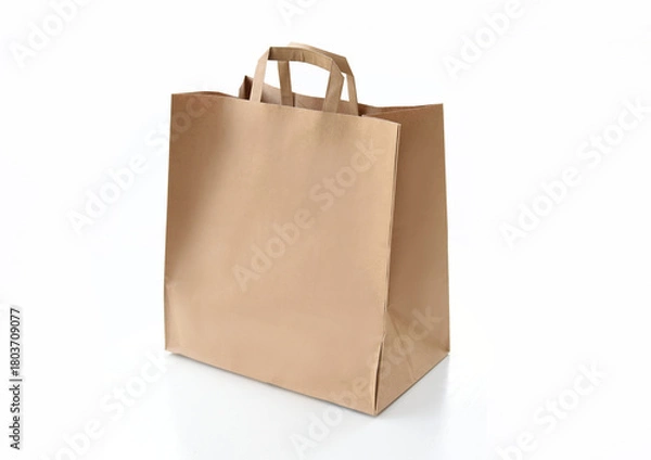 Obraz Plain kraft paper shopping bag with handles on a clean white background. Eco-friendly packaging concept for retail, delivery, gifts, or branding. Minimalistic studio shot of a reusable paper bag.
