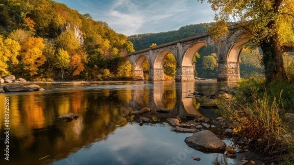 Fototapeta oxbow. Allegheny River flowing under a historic stone bridge with autumn trees and reflections. representing seasonal cycles and harvest abundance.