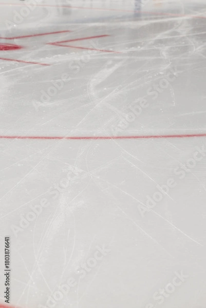 Fototapeta Ice scratched by skates on a hockey rink - closeup of the red markings