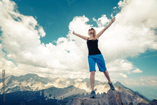 Fototapeta Young lady standing on top of the hill with raised hands