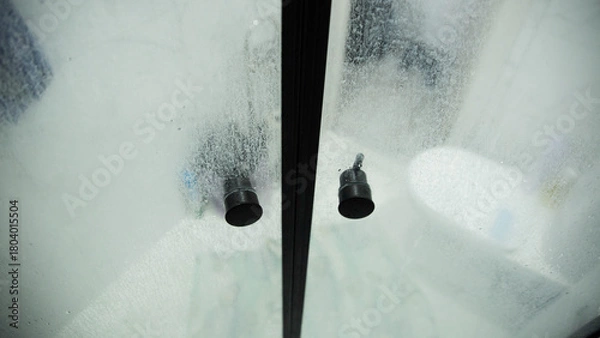 Fototapeta White marks and hard water stains on the transparent shower doors in the bathroom. Unsanitary and Hygiene Cleaning Solution, industry