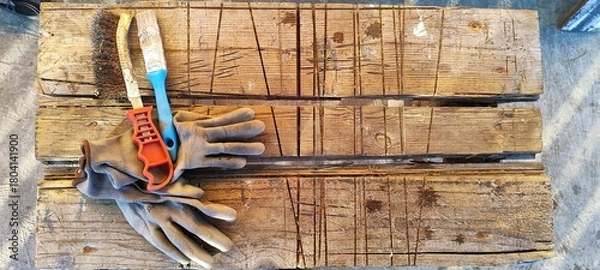 Fototapeta Work tools including gloves and brushes on a rustic wooden workbench. DIY and home improvement concept. Top view flat lay with copy space