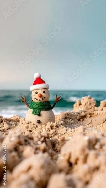 Fototapeta An adorable sandy snowman with a Santa hat and scarf brings holiday cheer to a sunny beach, celebrating a unique coastal Christmas
