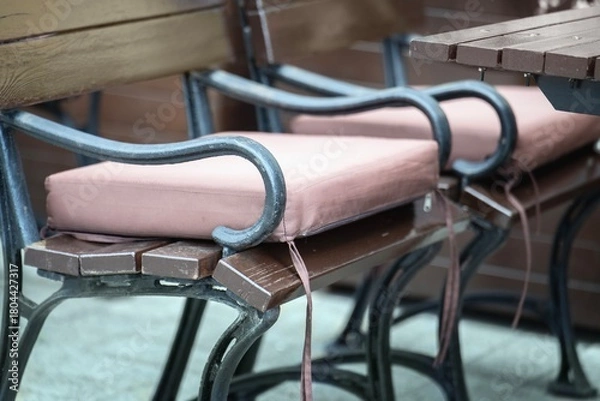 Fototapeta A soft pink waterproof fabric cushion on a bench in an outdoor cafe for guest comfort