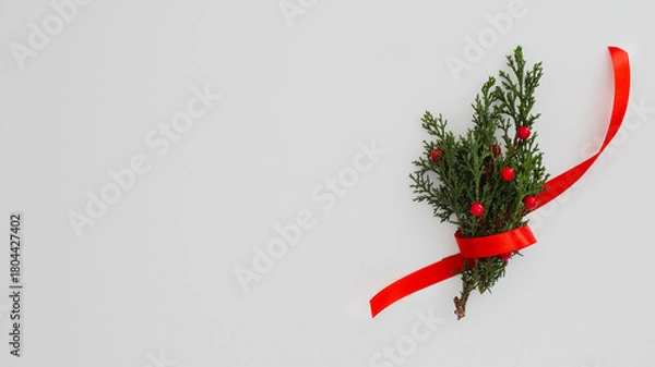Obraz A small evergreen sprig with red berries tied with a festive red ribbon on a plain background