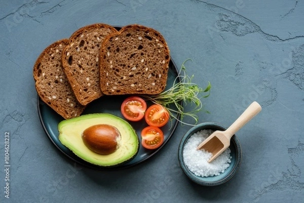 Obraz Healthy breakfast ingredients with dark bread avocado cherry tomatoes and salt on a plate
