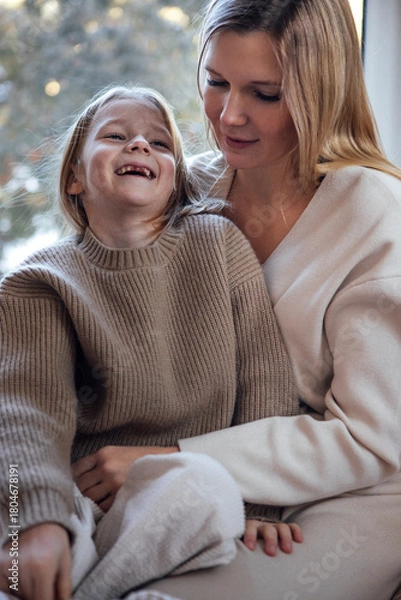 Obraz Woman and child, both in cozy knitwear, share a joyful moment indoors, surrounded by soft natural light, embodying warmth and connection in a serene atmosphere