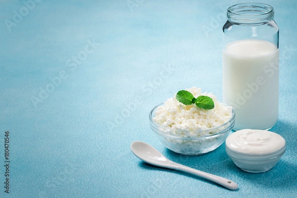 Fototapeta Fresh milk sour cream yogurt cottage cheese in glass bowls on blue background. Selective focus, copy space. 