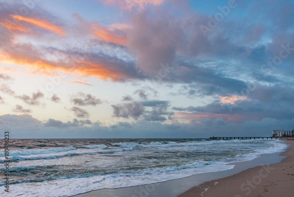 Obraz mostly cloudy skies over the ocean and pier at sunrise